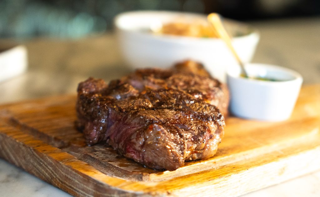 Grilled steak served on wooden board at an affordable steak house in Manhattan